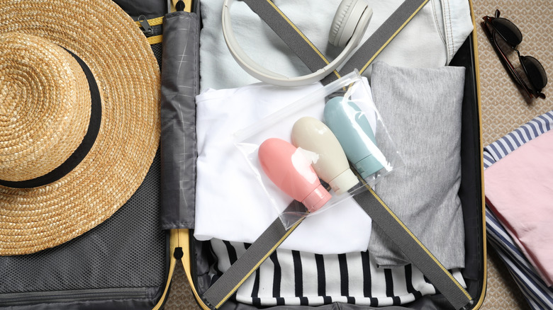 Travel-sized bottles in a bag placed inside an open suitcase