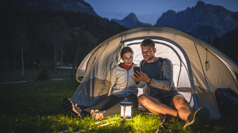 Couple with a camping lantern in front of a tent