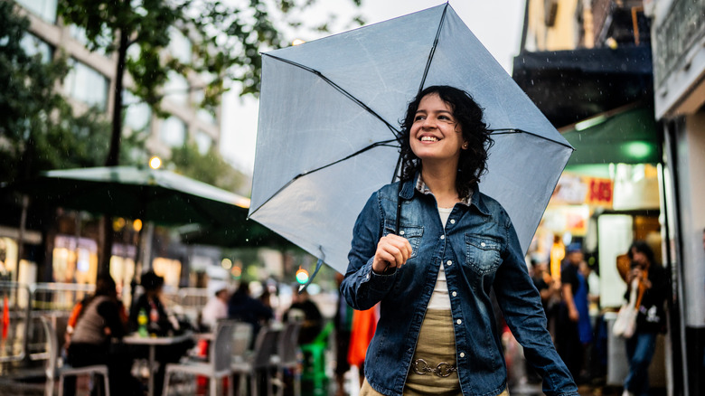 a young woman holding an umbrella while exploring a city