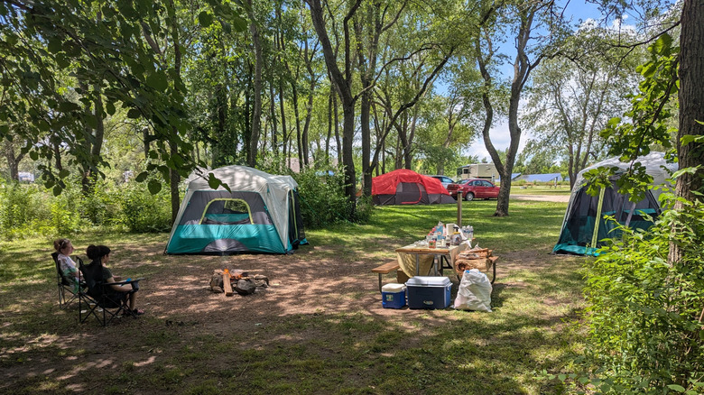 Tents, picnic table, and campers sitting near a fire at the Starved Rock Family Campground