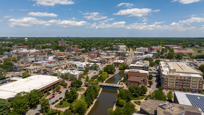 Expansive drone view of Naperville showing the downtown buildings, Riverwalk, neighborhoods, and green spaces in summer
