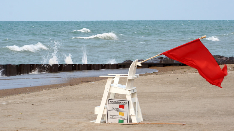 An empty lifeguard chair on the sandy shore at Kenilworth Beach with Lake Michigan waves rolling in on a windy day.