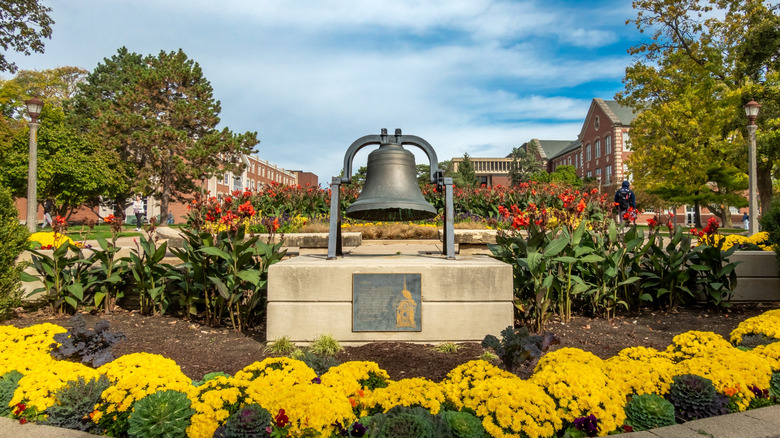 Brass bell above flower bed, marking Illinois State University campus