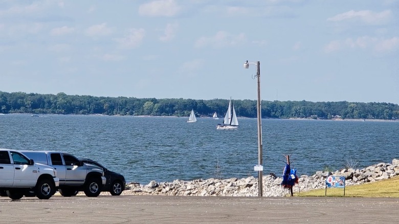 Trucks parks at the boat ramp at South Shore Park in Illinois, featuring a lake with choppy waters and sailboats in the distance.