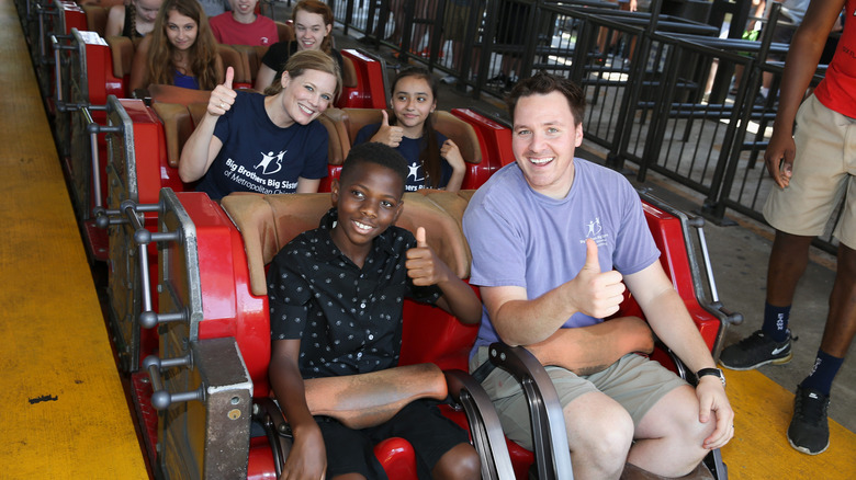Adults and kids doing thumbs up on roller coaster