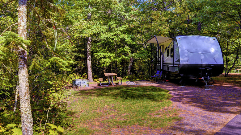 A caravan set up at a forested campsite with a picnic table at Rock Cut State Park, Illinois