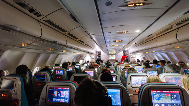 A flight cabin with rows of seated people