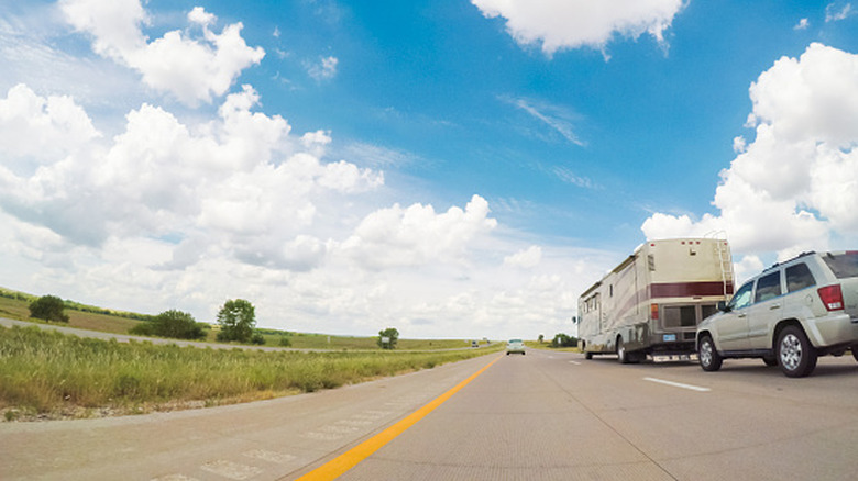 An RV towing a car, driving along the highway in the Midwest