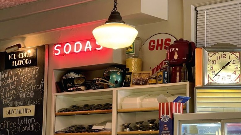 The interior of the South Side Soda Shop, showing a neon sign reading Sodas and old-fashioned decor