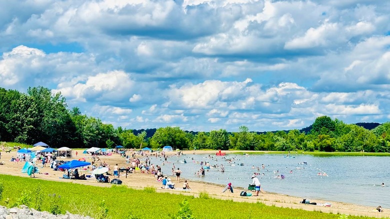 Beachgoers with umbrellas and towels enjoying Fairfax Beach on Monroe Lake in Indiana