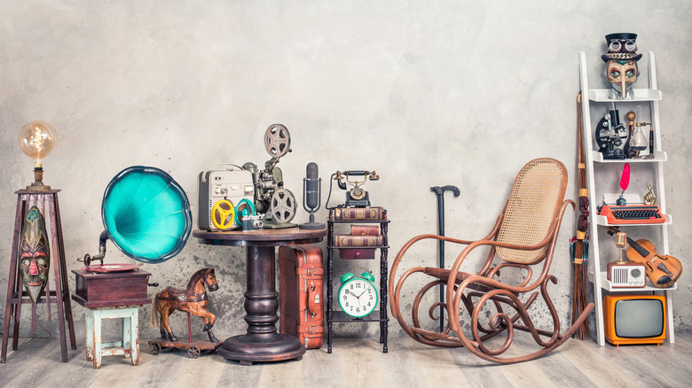 A wide range of antique objects are arranged in a line against a blank wall