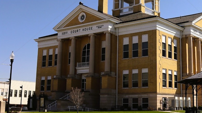 The yellow-brick Boonville Court House encircled by gassy lawns, parked cars, and historic shopfronts in Boonville, Warrick County.