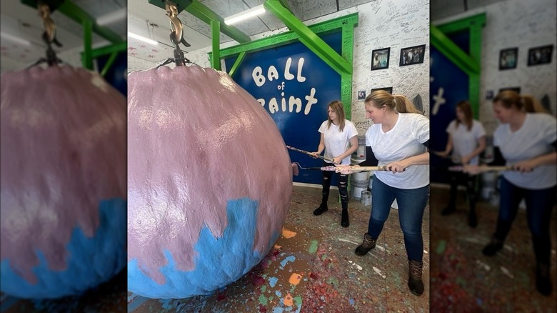 Women paint a layer on the World's Largest Ball of Paint
