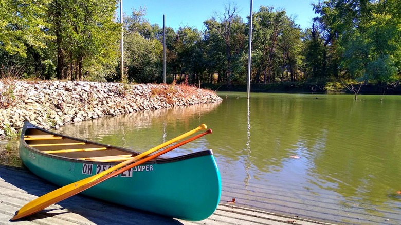A green canoe with yellow paddles sits on the Tanners Creek boat ramp in Lawrenceburg Indiana