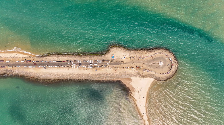 Aerial view of a road flanked by sandy beaches and green water on both sides