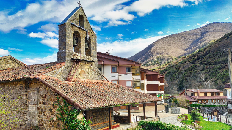 The Church of Santa Eulalia in Posada de Valdeón with the village around it and mountains in the distance
