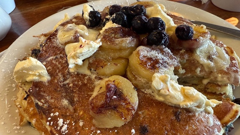 Buttermilk pancakes with banana, cream, and blueberries on top at Bluebird Cafe.