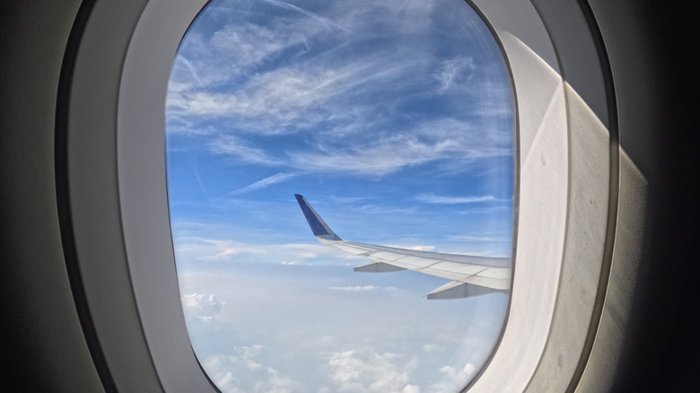 View of beautiful clouds and airplane wings from the window with beautiful blue sky