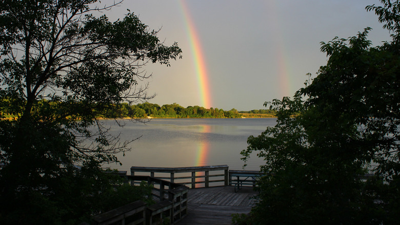 A rainbow, reflected in the water of Big Creek Lake, at a fishing pier