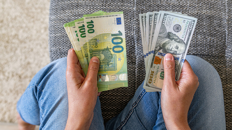 Person holding euro and dollars side by side