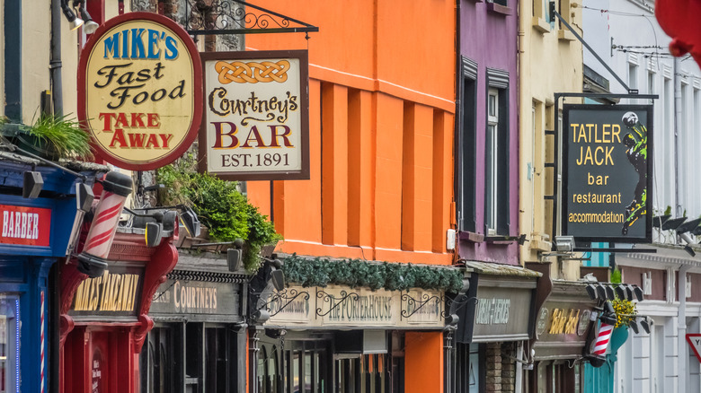 a close up of pub signs and colorful buildings in Killarney, Ireland