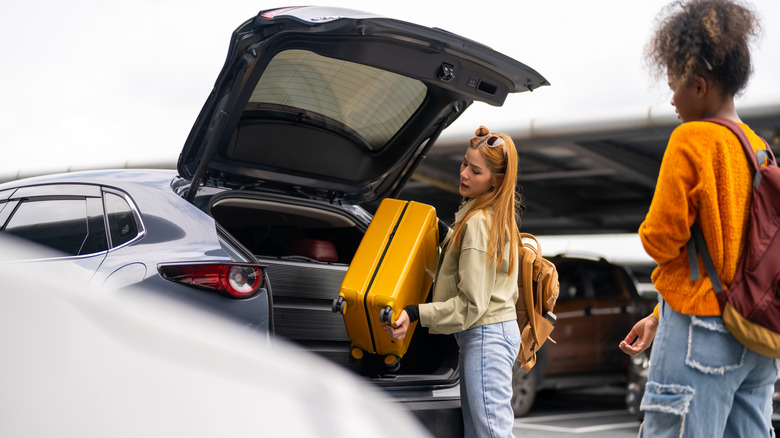 travelers putting luggage in their rental car
