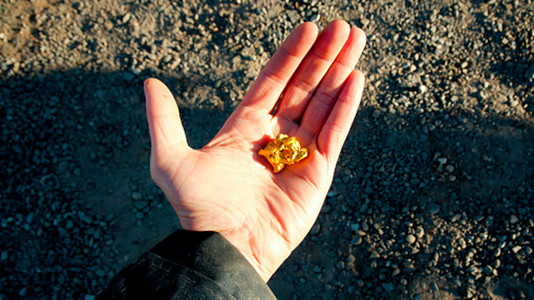 hand holding gold nugget outside