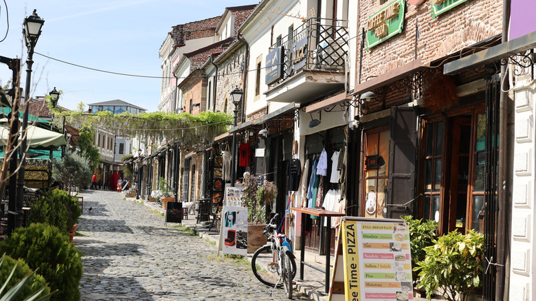 Shops line cobblestone street on sunny day in Korce, Albania