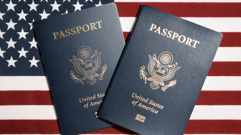 Two United States of America passports in front of a U.S. flag