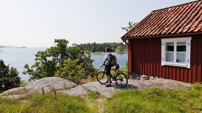 A cyclist beside a red hut on an island
