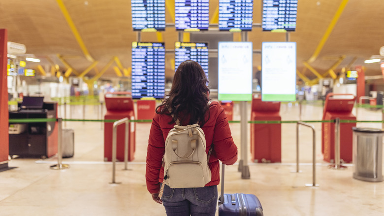 Woman at an airport looking at departures board