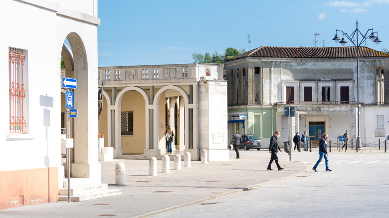 People walking among rationalist buildings in Tresigallo, Italy