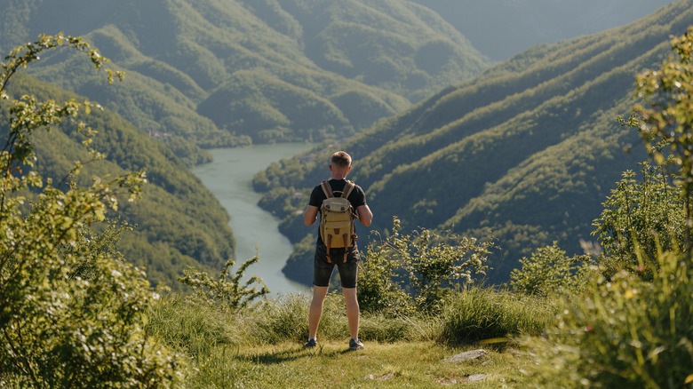 A hiker looks over the green valleys of the Apuan Alps