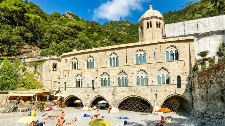 People sunbathing on a pebbled beach in San Fruttuoso, Camogli