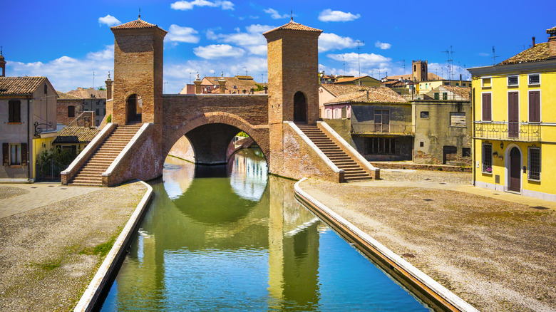 the famous Ponte dei Trepponti over green river and surrounded by houses