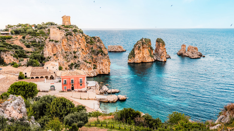 rocky bluffs, villa, and a bay with turquoise water