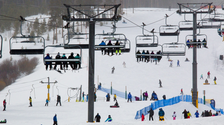 People skiing on ski slope at Breckenridge ski resort near Village Road on a cold snowy winter day during Ullr Festival in Rocky Mountains