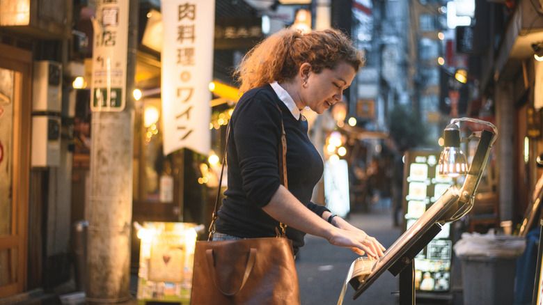 A tourist looking at a menu in an alley in Japan