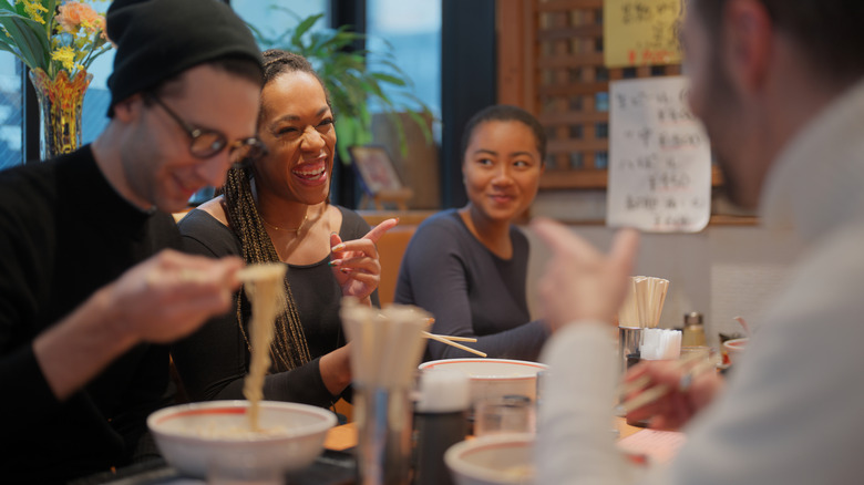 A multicultural group eating noodles in a Japanese restaurant