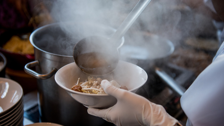 Chef plating a steaming bowl of ramen at a Japanese restaurant