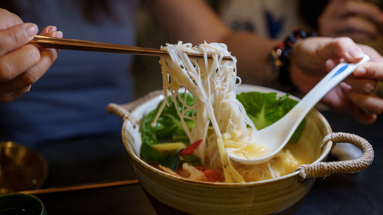 Eating a bowl of ramen with spoon and chopsticks