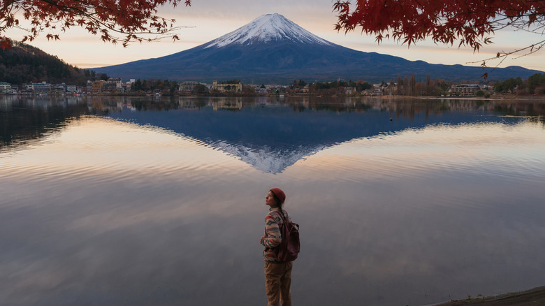 Mount Fuji reflected on the water with a hiker in the foreground