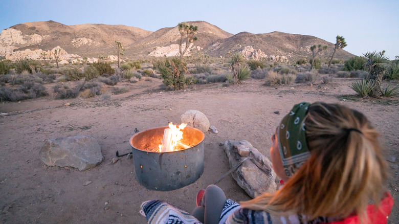 Woman sitting next to a fire pit in the desert