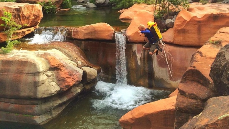 Man jumpming into Maiden Falls as it cascades into waters below