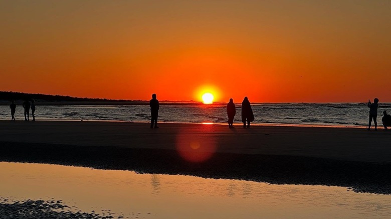 People on the beach during a sunrise over Hog Inlet, South Carolina