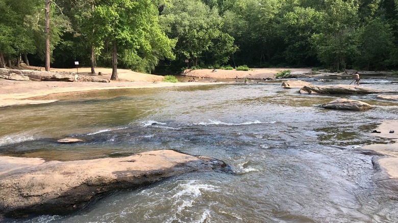 The North Oconee River at Hurricane Shoals Park, Georgia, with a kids in the distance playing in the water and on the rocks