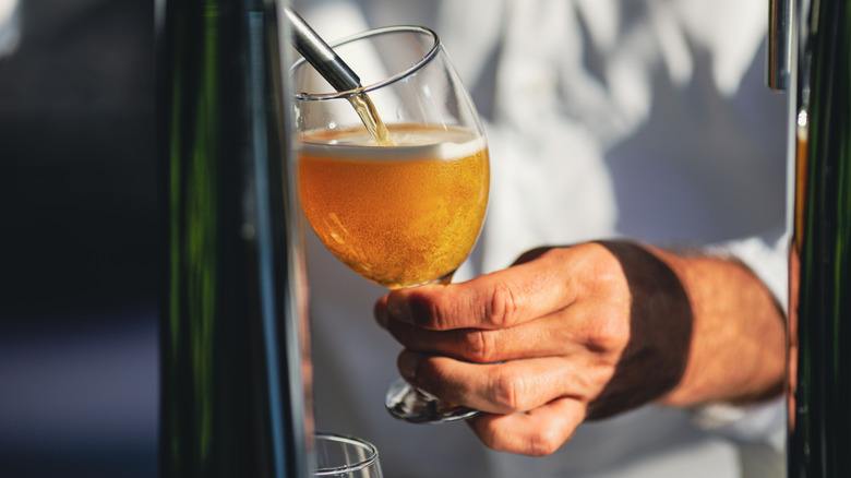 Server pouring cider into a glass from a dispenser