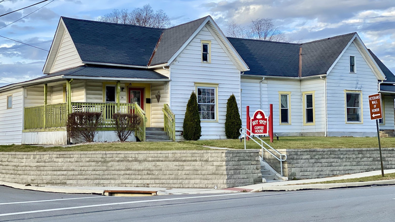 Exterior of Hot Spot Coffee House in Johnstown, Ohio, a cozy white house-style café with a porch and a red roadside sign