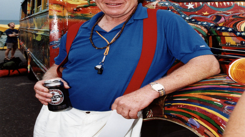 Ken Kesey stands in front of a colorful bus in the United Kingdom