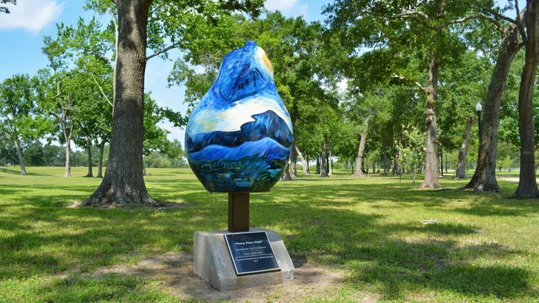 Large painted sculpture shaped like a pear surrounded by trees in a park in Pearland, Texas